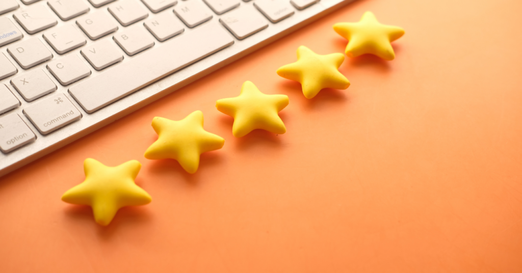 オレンジのテーブルに白のキーボードと星が5つおかれている。口コミの星のイメージ画像