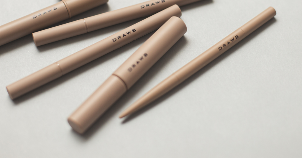 DRAWBシリーズの化粧品がグレーのテーブルにランダムに置かれている