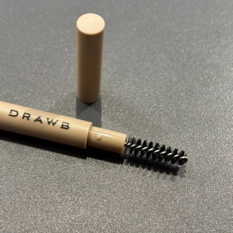 ブラックのテーブルの上に置かれているDRAWBのスクリューブラシとキャップ付きであることがわかる画像。